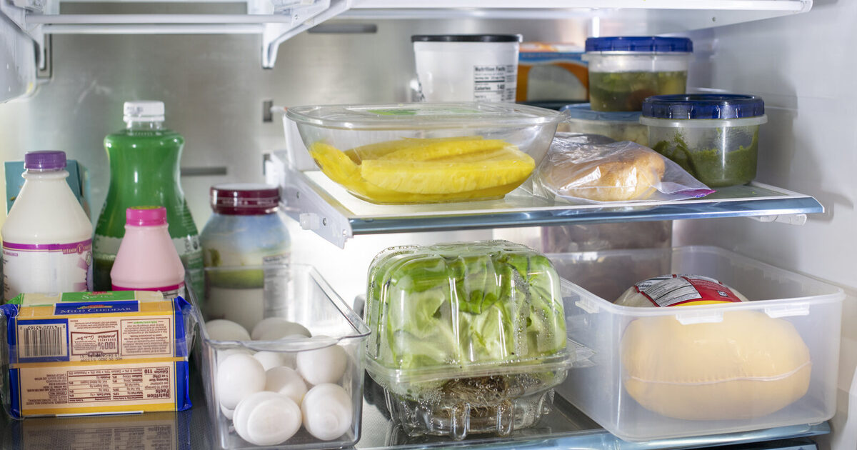 A real household refrigerator containing sealed leftovers, dairy, eggs, produce, bread, and cheese