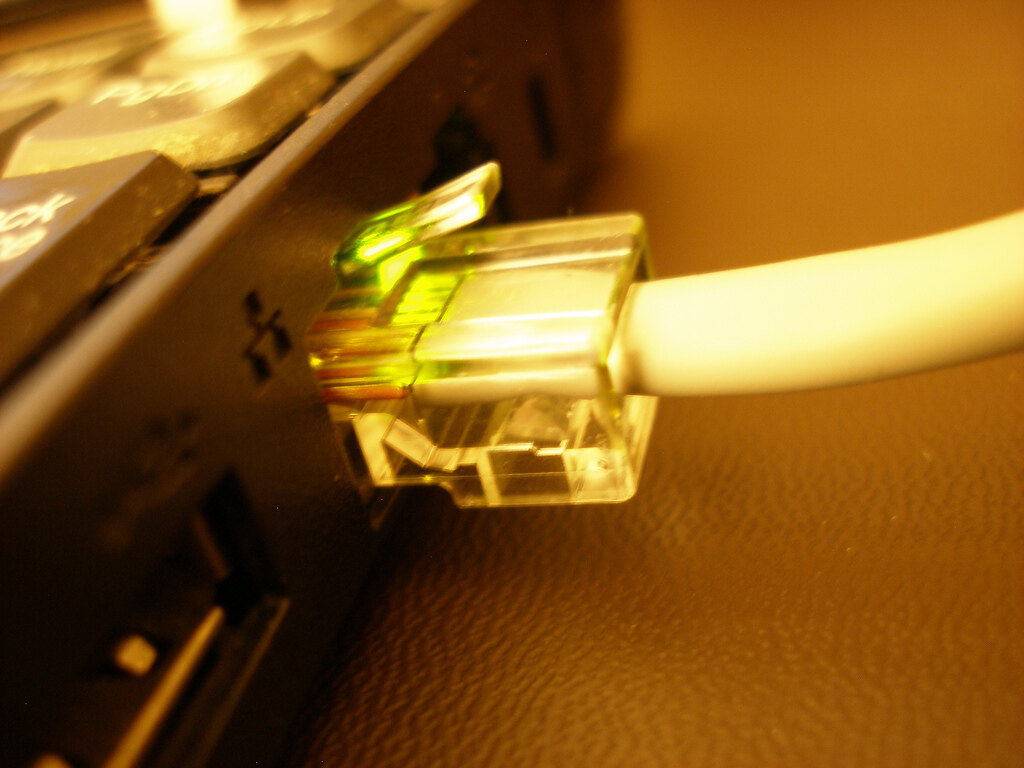 A real Ethernet cable with a clear RJ45 plug connected to a laptop