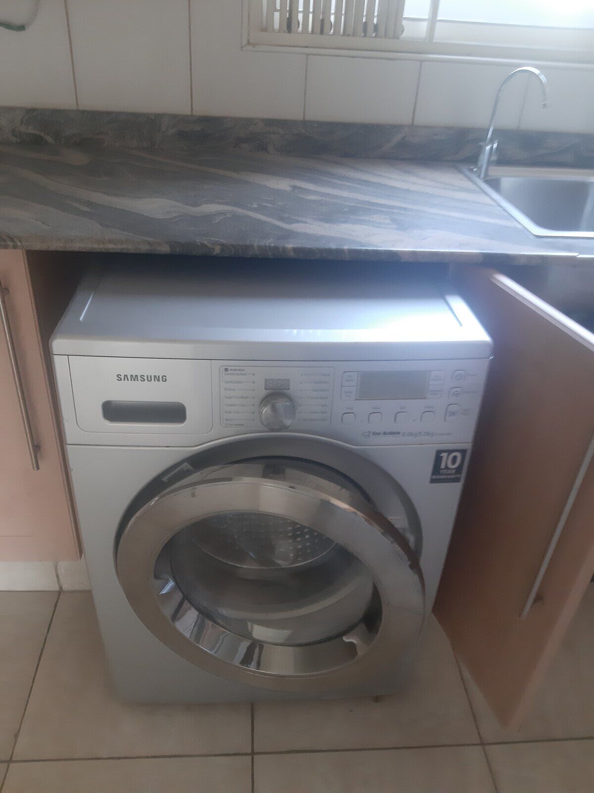 A real front-loading washing machine installed beside a kitchen counter